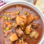 apple cider beef stew in two white bowls on a wooden table