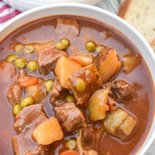 apple cider beef stew in two white bowls on a wooden table