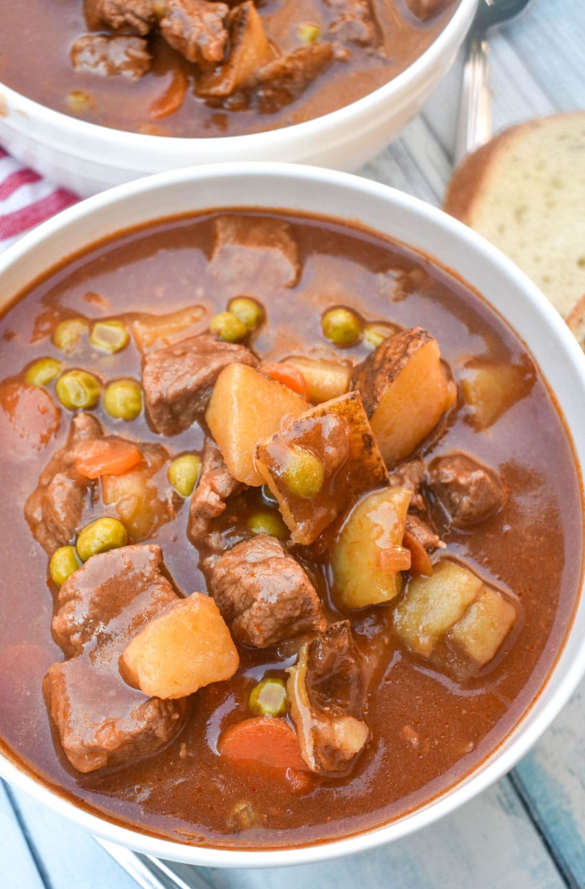 apple cider beef stew in two white bowls on a wooden table