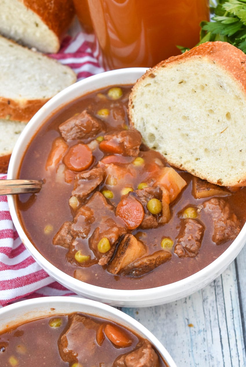 apple cider beef stew in two white bowls on a wooden table