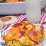 a slice of egg mcmuffin casserole on a small white plate with a glass of milk in the background