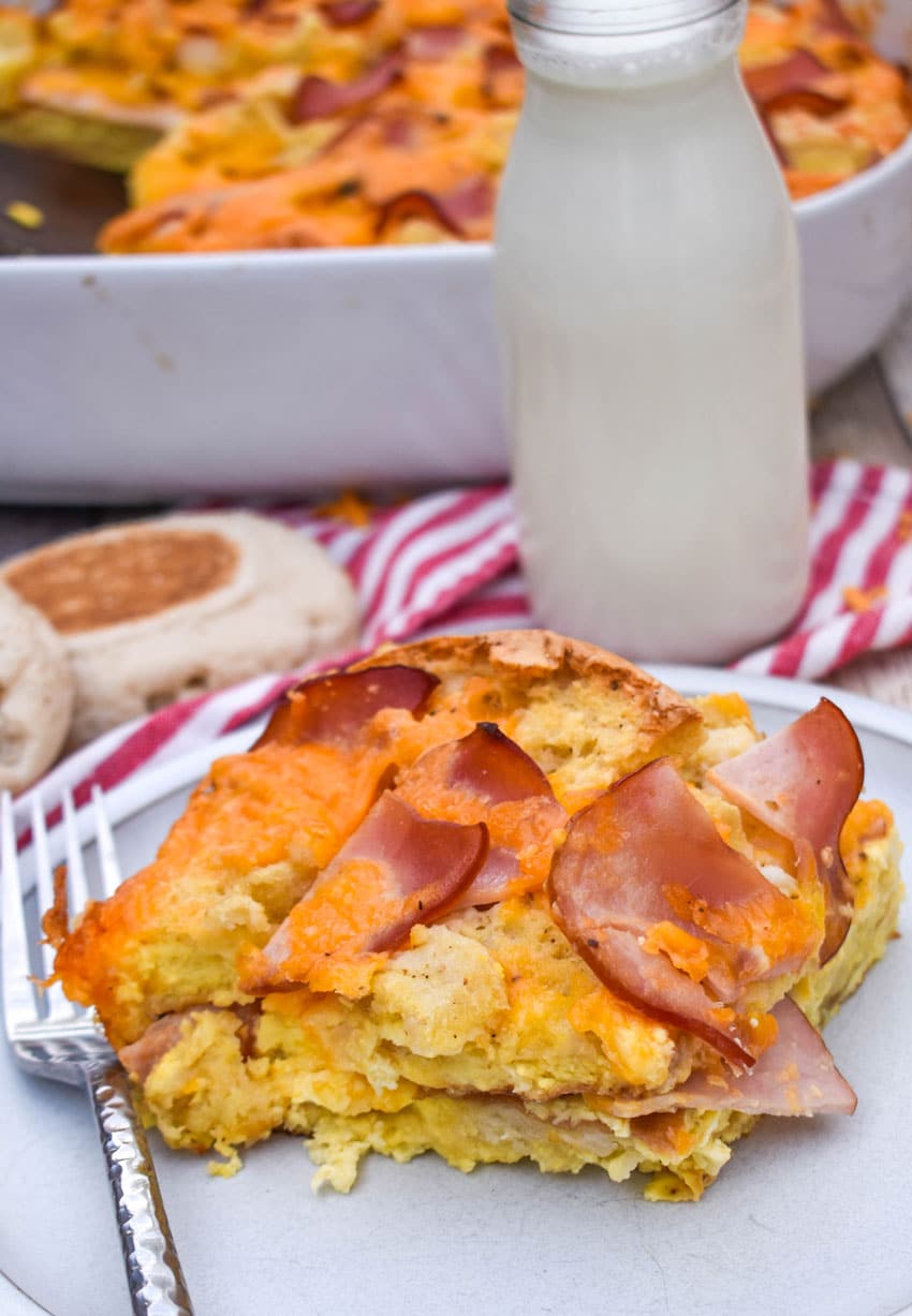 a slice of egg mcmuffin casserole on a small white plate with a glass of milk in the background