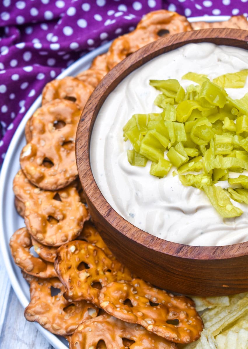 mississippi pot roast dip in a small wooden bowl surrounded by chops and pretzels for dipping