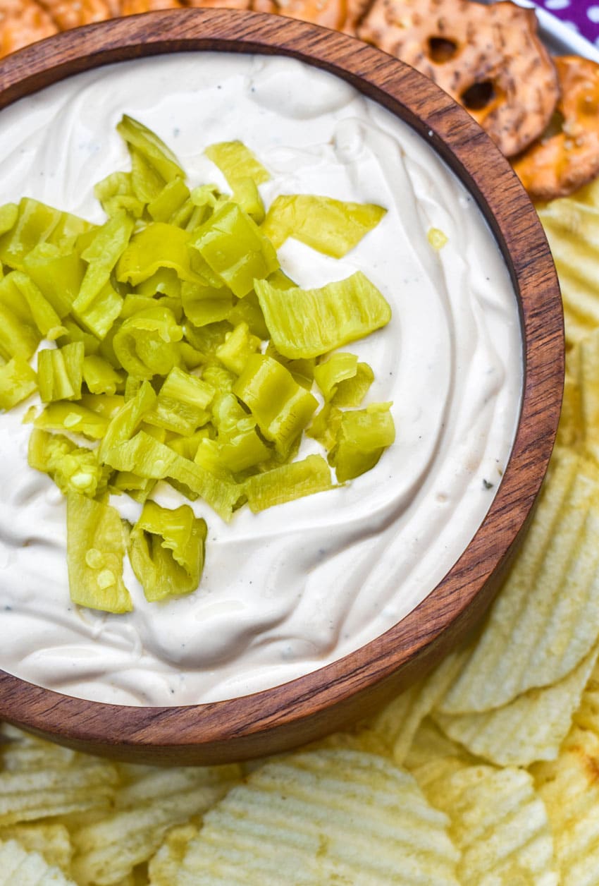 mississippi pot roast dip in a small wooden bowl surrounded by chops and pretzels for dipping