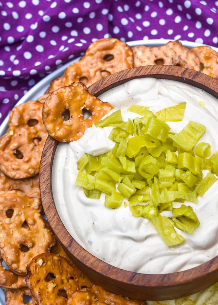 mississippi pot roast dip in a small wooden bowl surrounded by chops and pretzels for dipping
