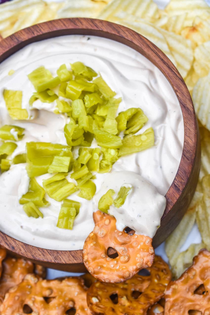 a pretzel chip scooping mississippi pot roast dip out of a wooden bowl