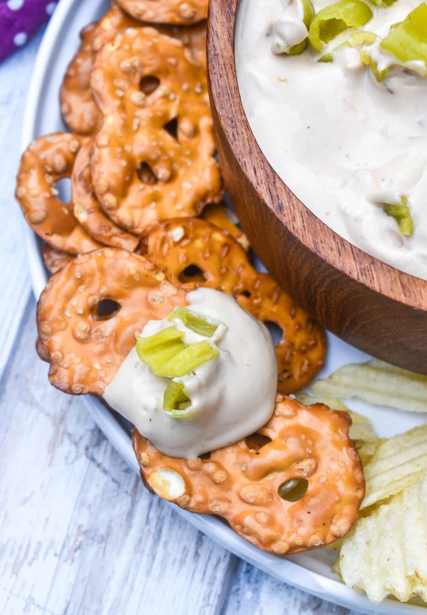 a pretzel chip scooping mississippi pot roast dip out of a wooden bowl