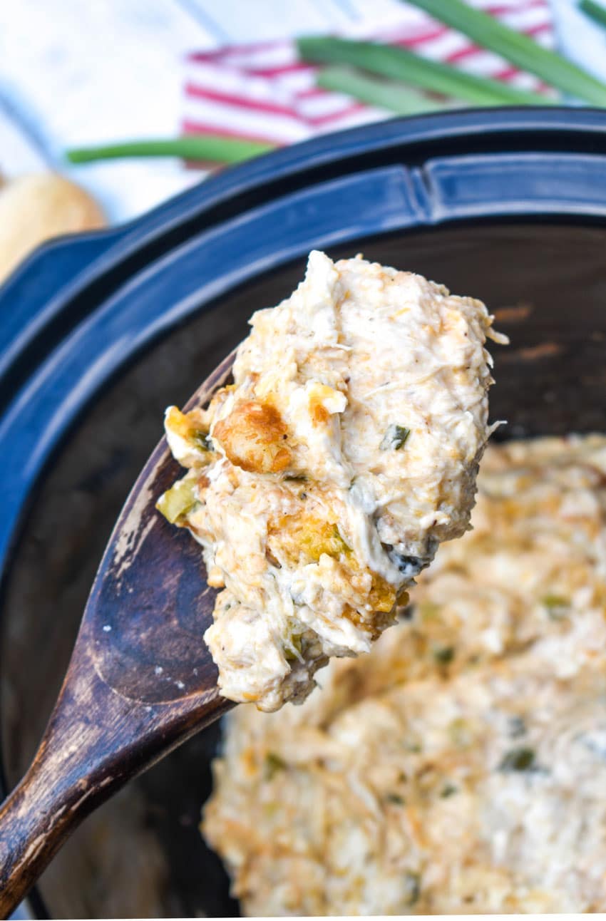 a wooden spoon holding up a scoop of creamy crab dip