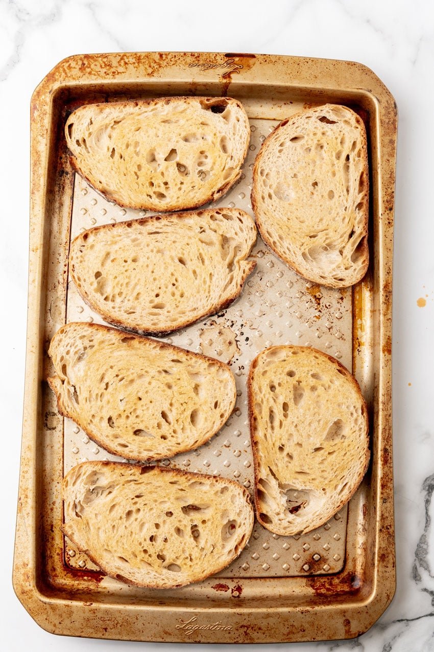 buttered slices of bread arranged on a metal baking sheet