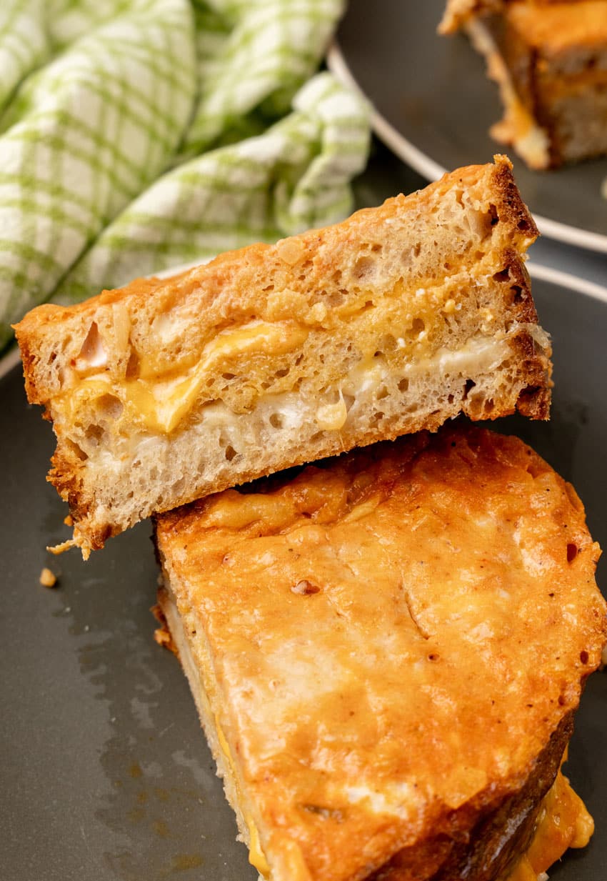 two halves of a tomato soup grilled cheese on a black plate