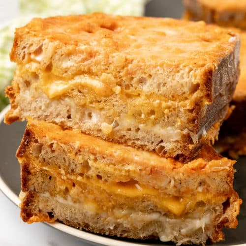 two halves of a tomato soup grilled cheese stacked on a black plate