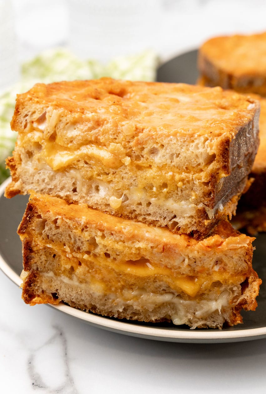 two halves of a tomato soup grilled cheese stacked on a black plate