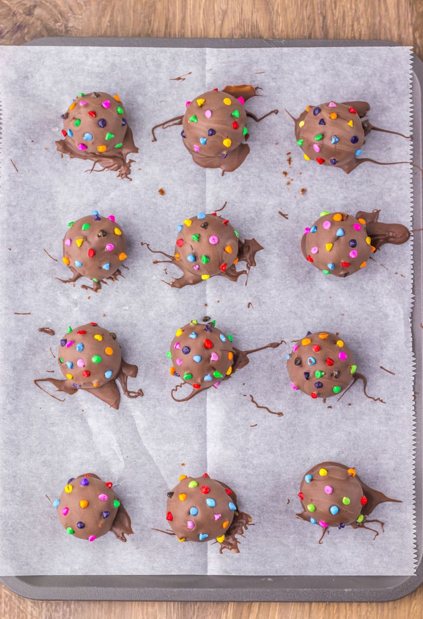 homemade cosmic brownie truffles arranged in rows on a parchment paper lined baking sheet