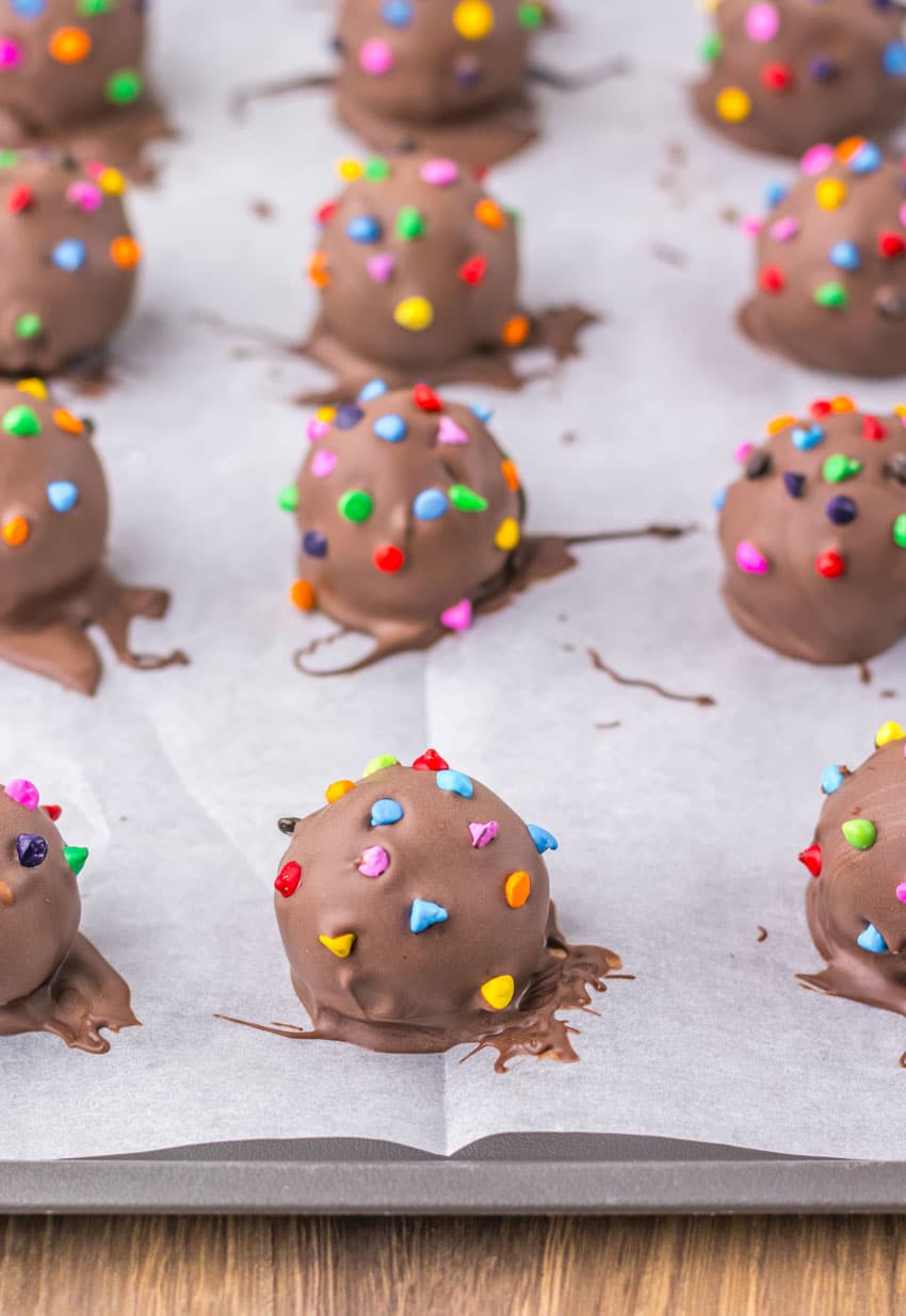 homemade cosmic brownie truffles arranged in rows on a parchment paper lined baking sheet