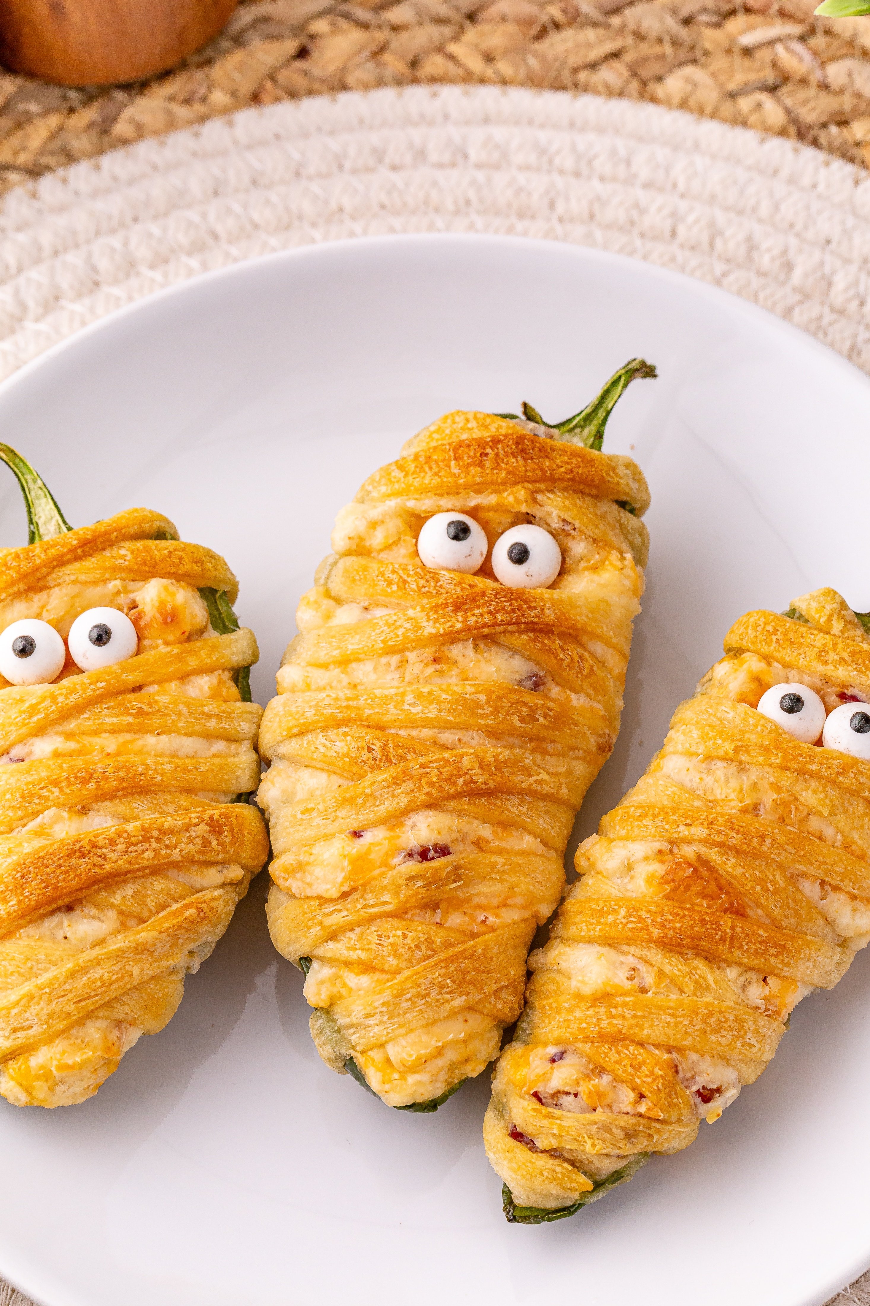 a close up image of jalapeno popper mummies on a white plate