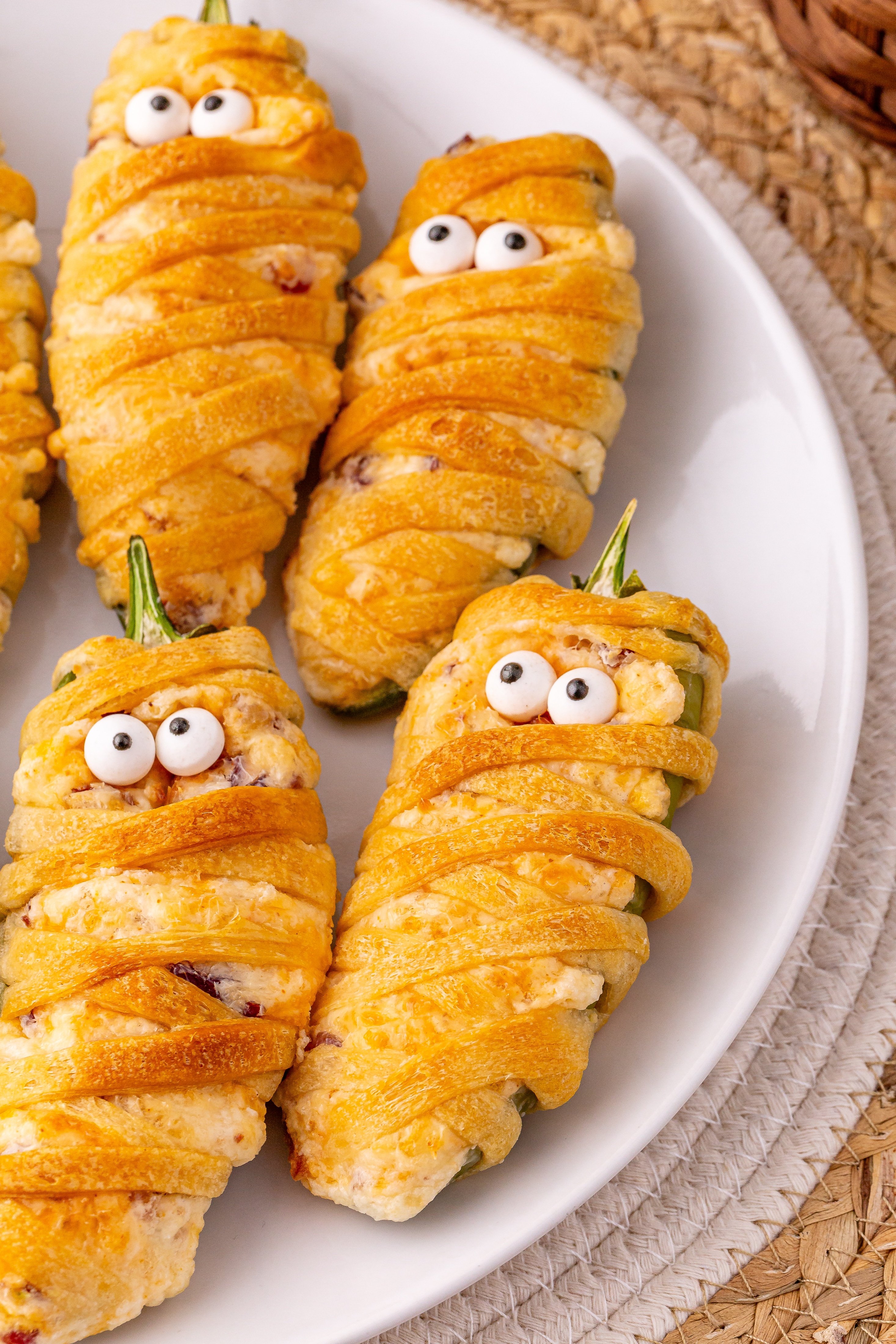 a close up image of jalapeno popper mummies on a white plate