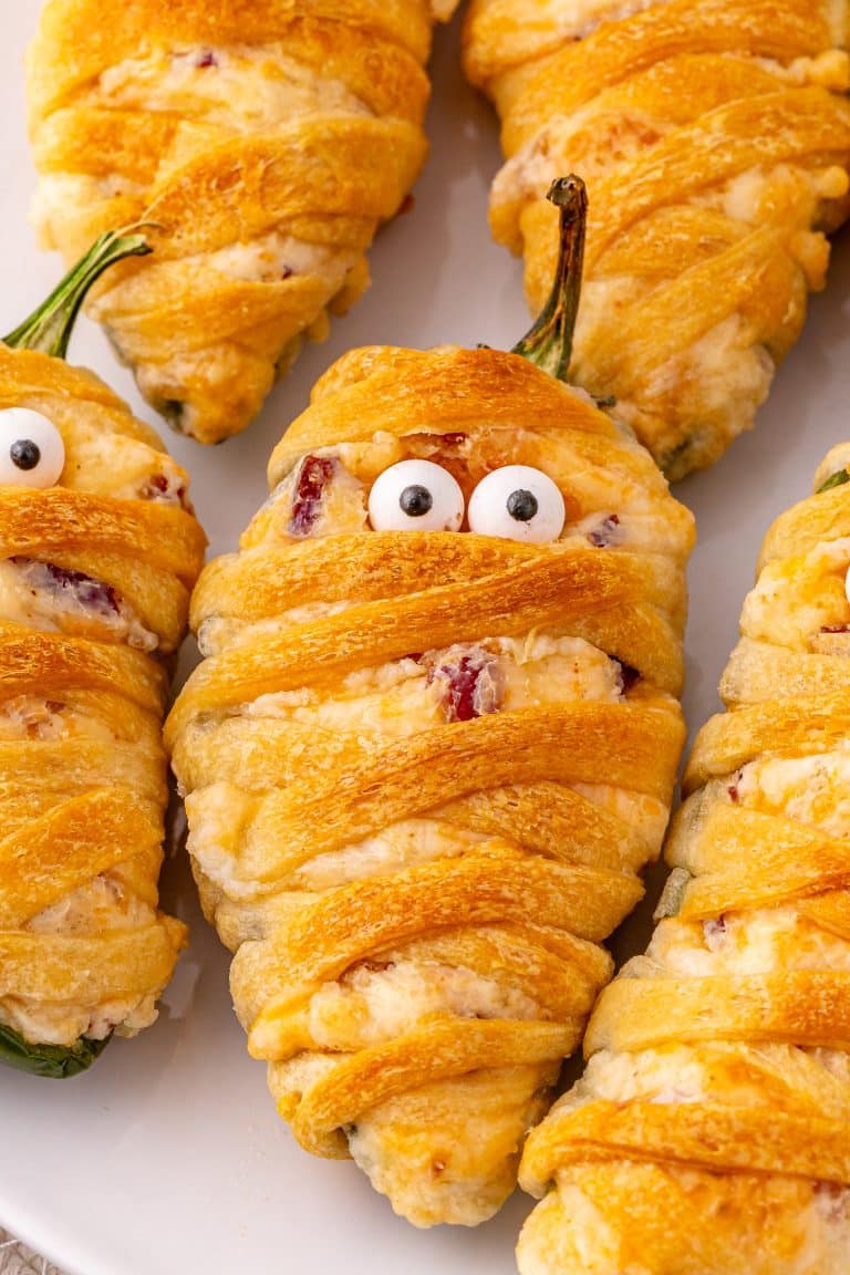 a close up image of jalapeno popper mummies on a white plate
