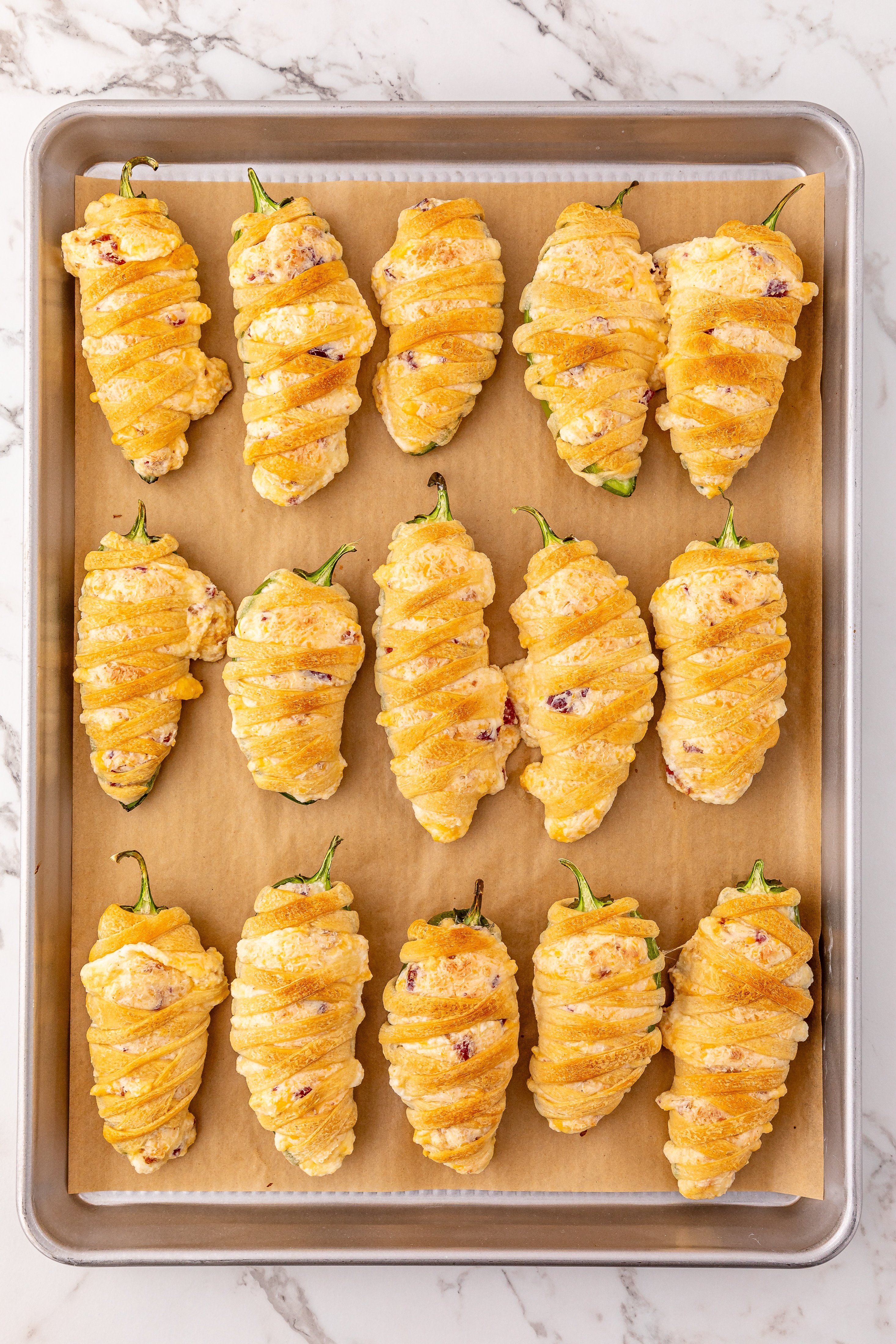 baked bacon cheddar jalapeno poppers on a sheet of brown parchment paper