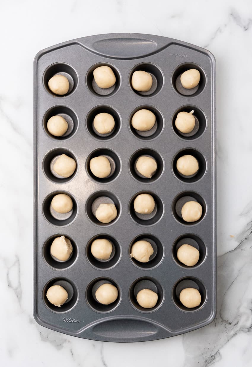 balls of sugar cookie dough in mini muffin tin wells