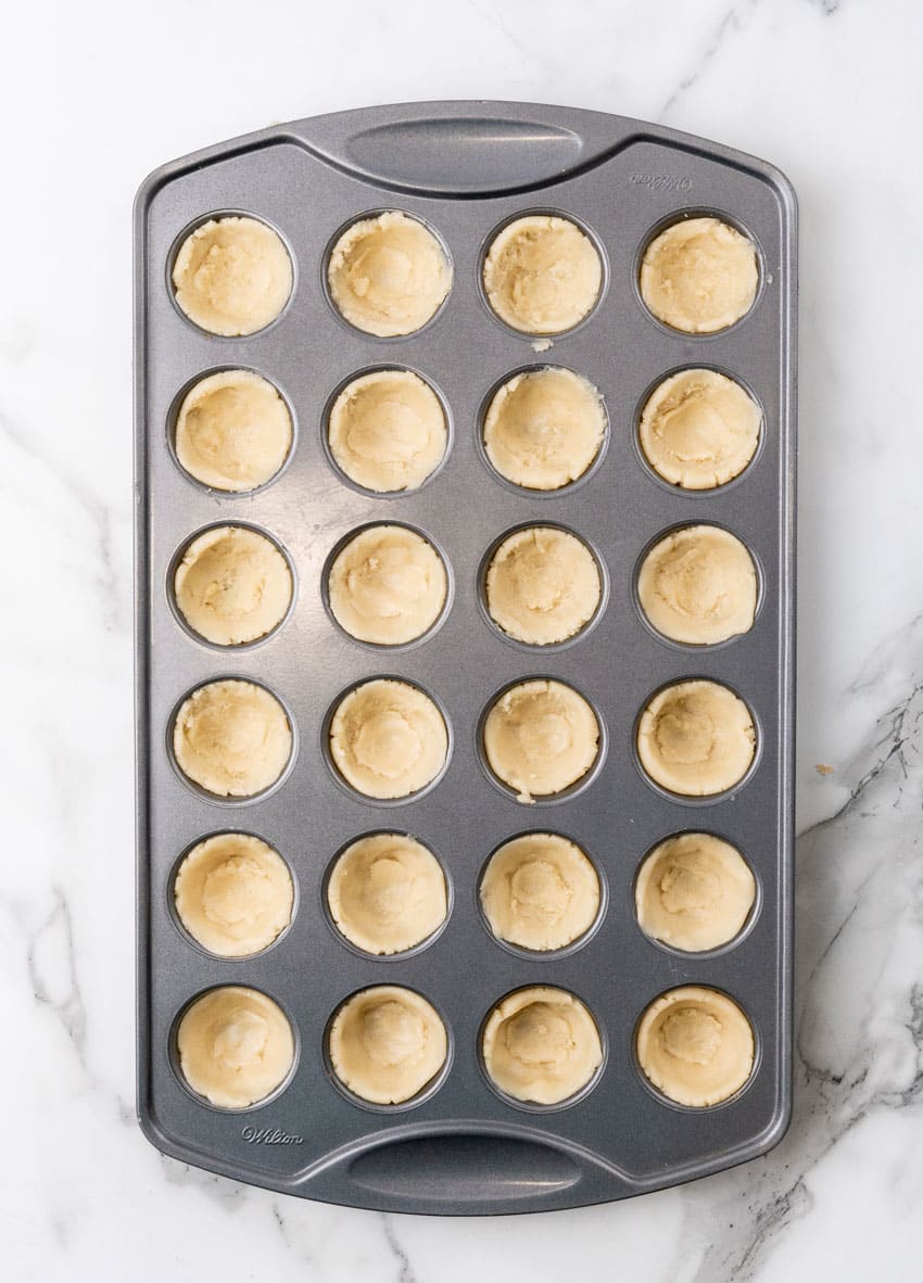 sugar cookie dough pressed into the wells of a mini muffin tin pan