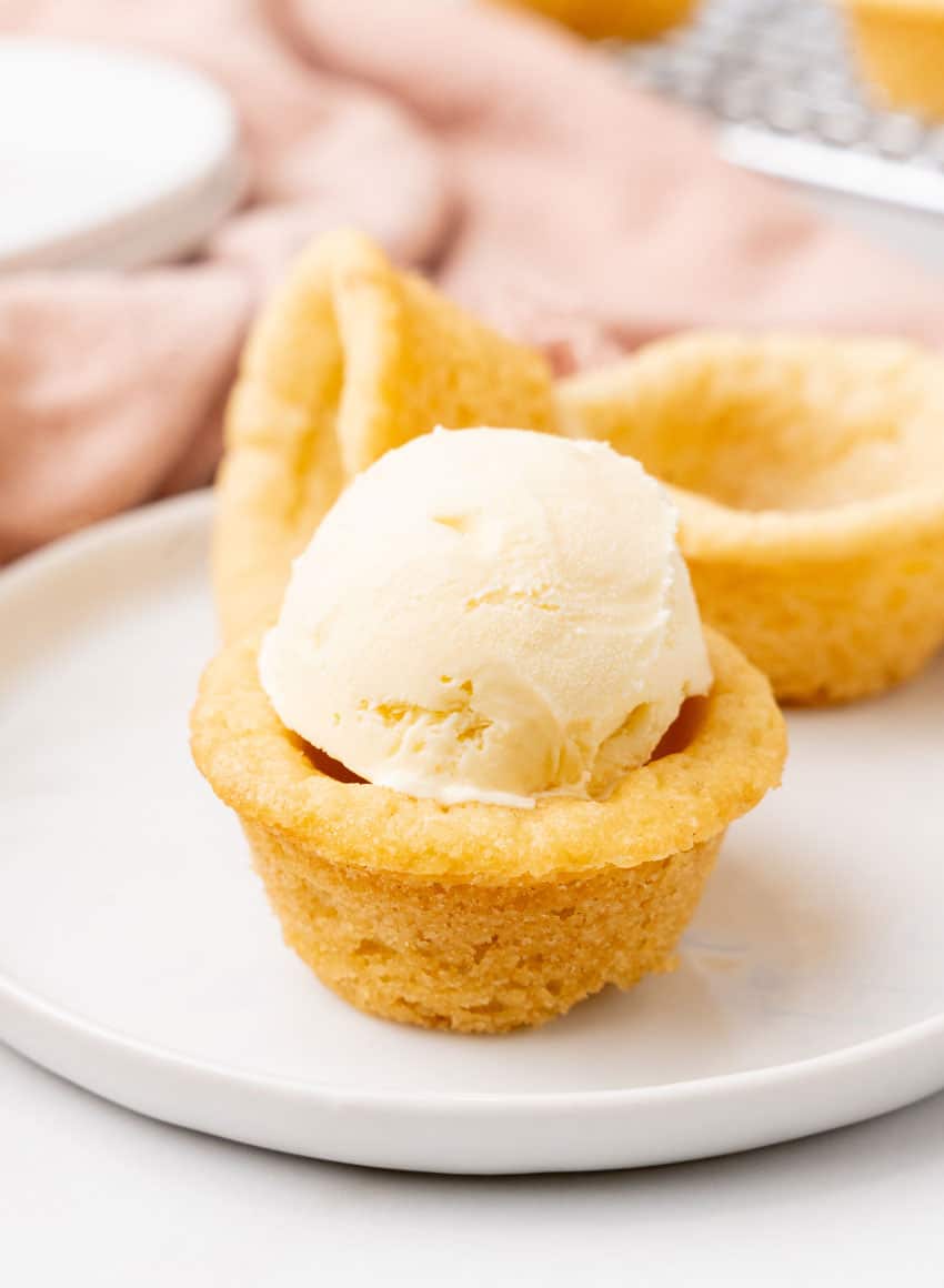 homemade sugar cookie cup filled with a scoop of vanilla ice cream on a small white dessert plate
