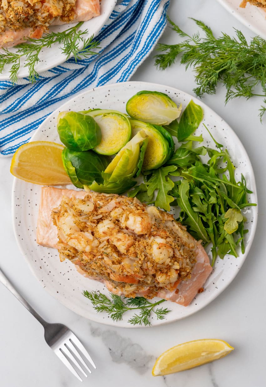 crab stuffed salmon next to leafy greens on a white plate