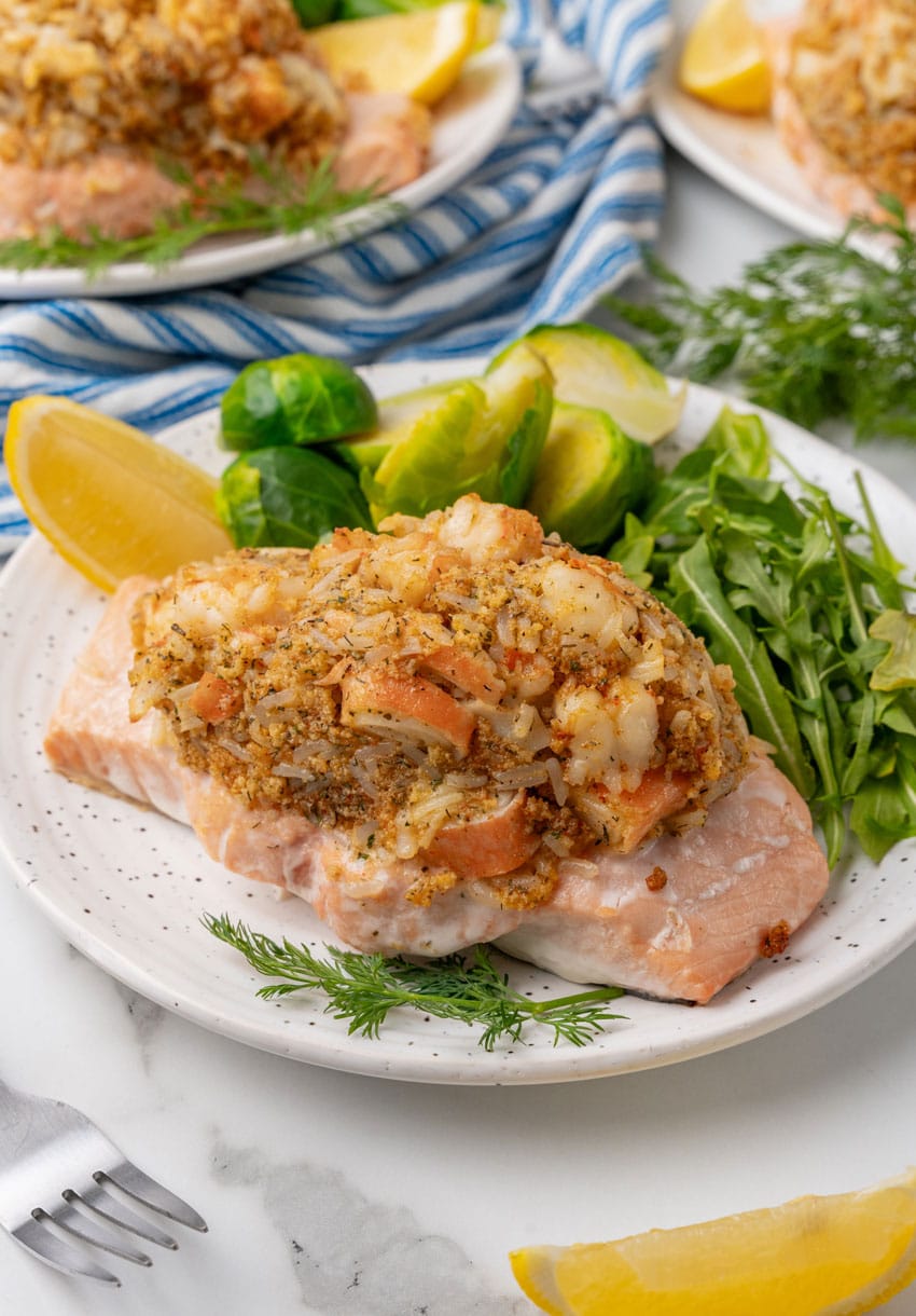 crab stuffed salmon next to leafy greens on a white plate