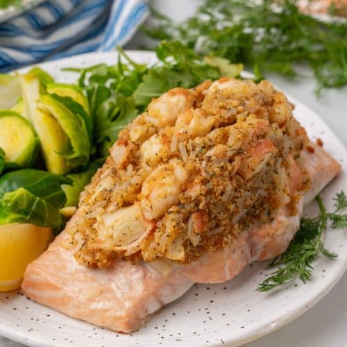 crab stuffed salmon next to leafy greens on a white plate