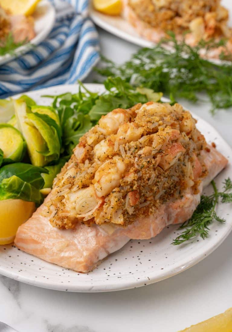 crab stuffed salmon next to leafy greens on a white plate
