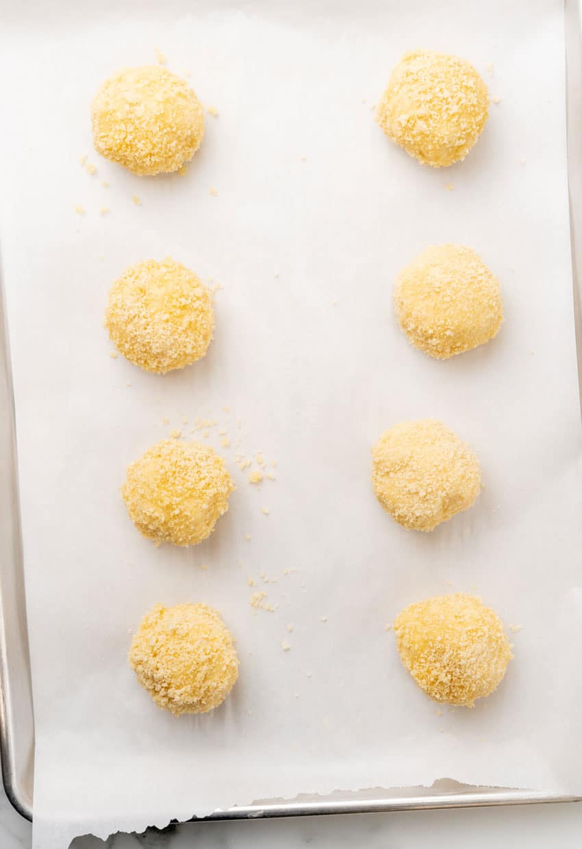 unbaked chicken pillows arranged in two rows on a parchment paper lined baking sheet