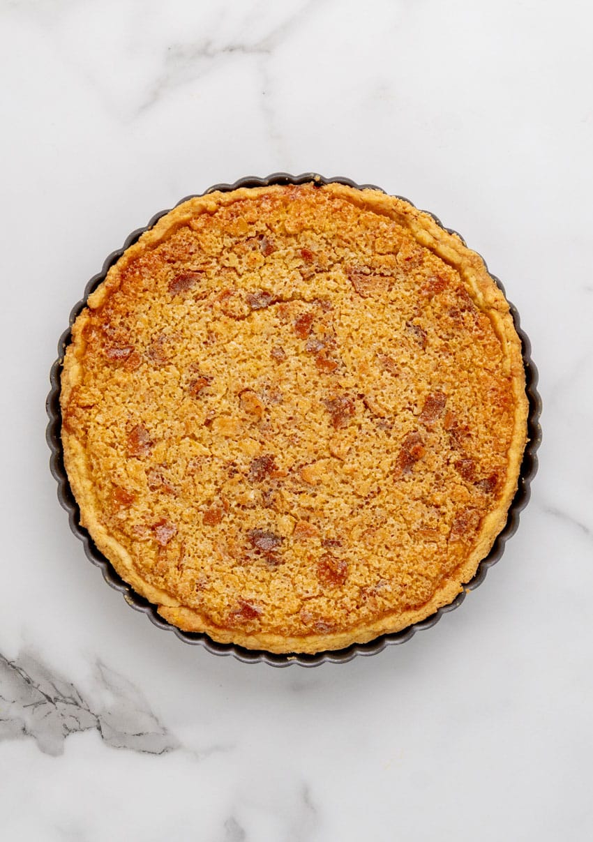 a baked treacle tart resting on a marble counter