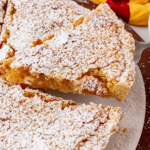 a slice of treacle tart being lifted of a white serving platter