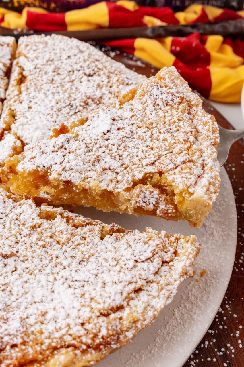 a slice of treacle tart being lifted of a white serving platter