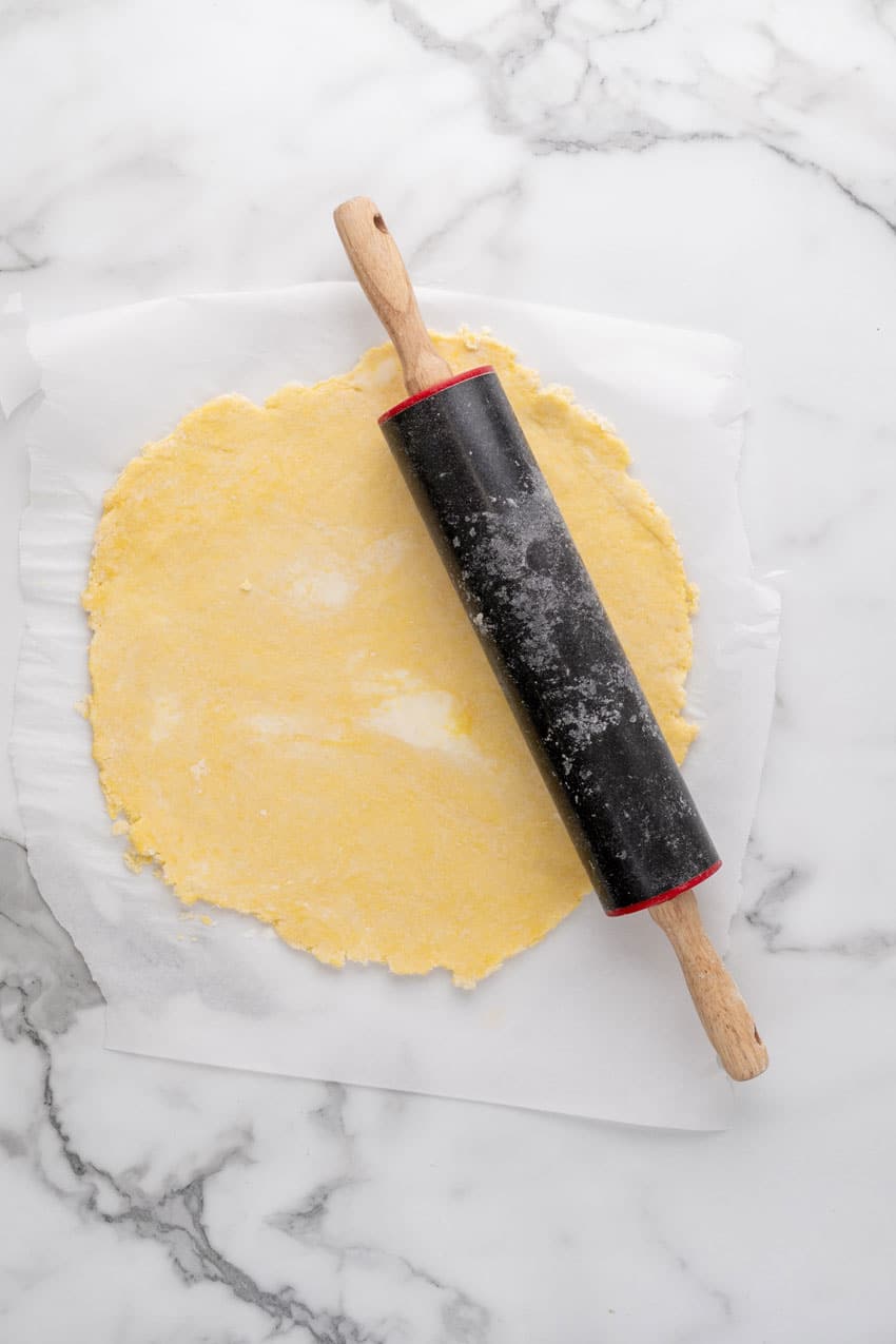 a homemade tart crust rolled out on a sheet of white parchment paper