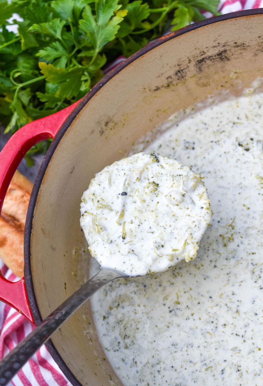a silver ladle holding up a scoop of homemade cream of broccoli soup