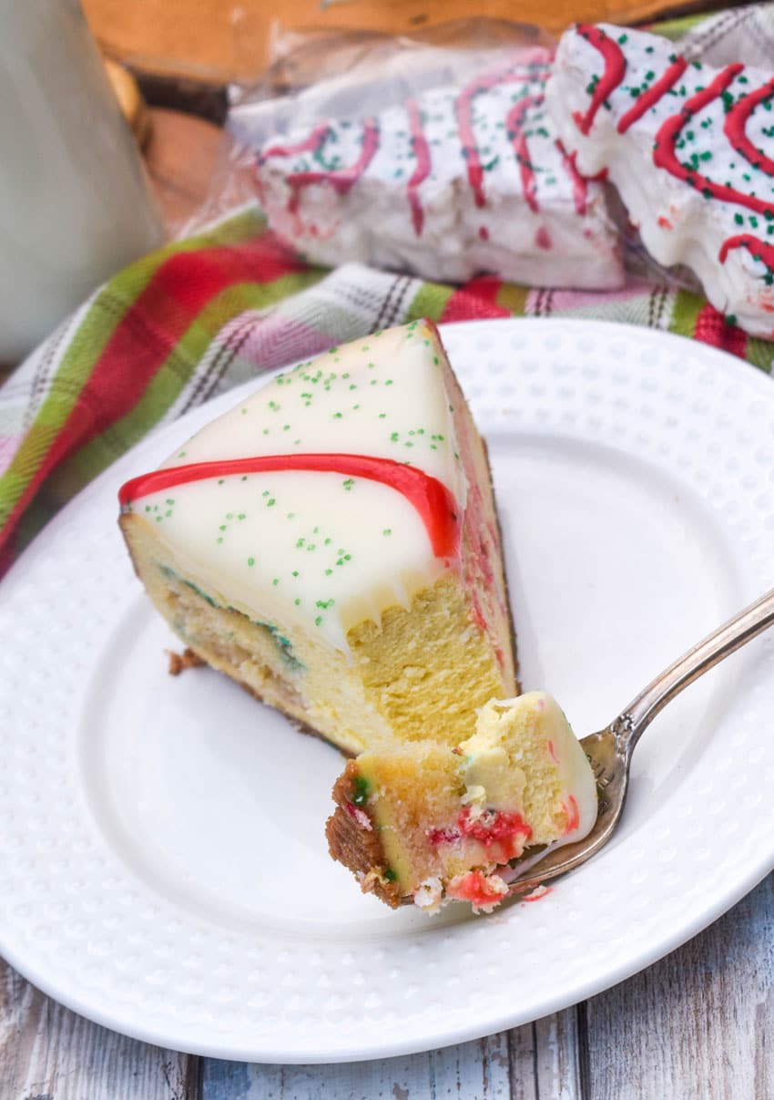 a silver fork holding a piece of little debbie christmas tree cheesecake resting on the edge of a white plate