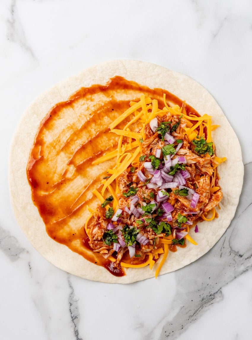 a barbecue chicken quesadillas being assembled on a marble countertop