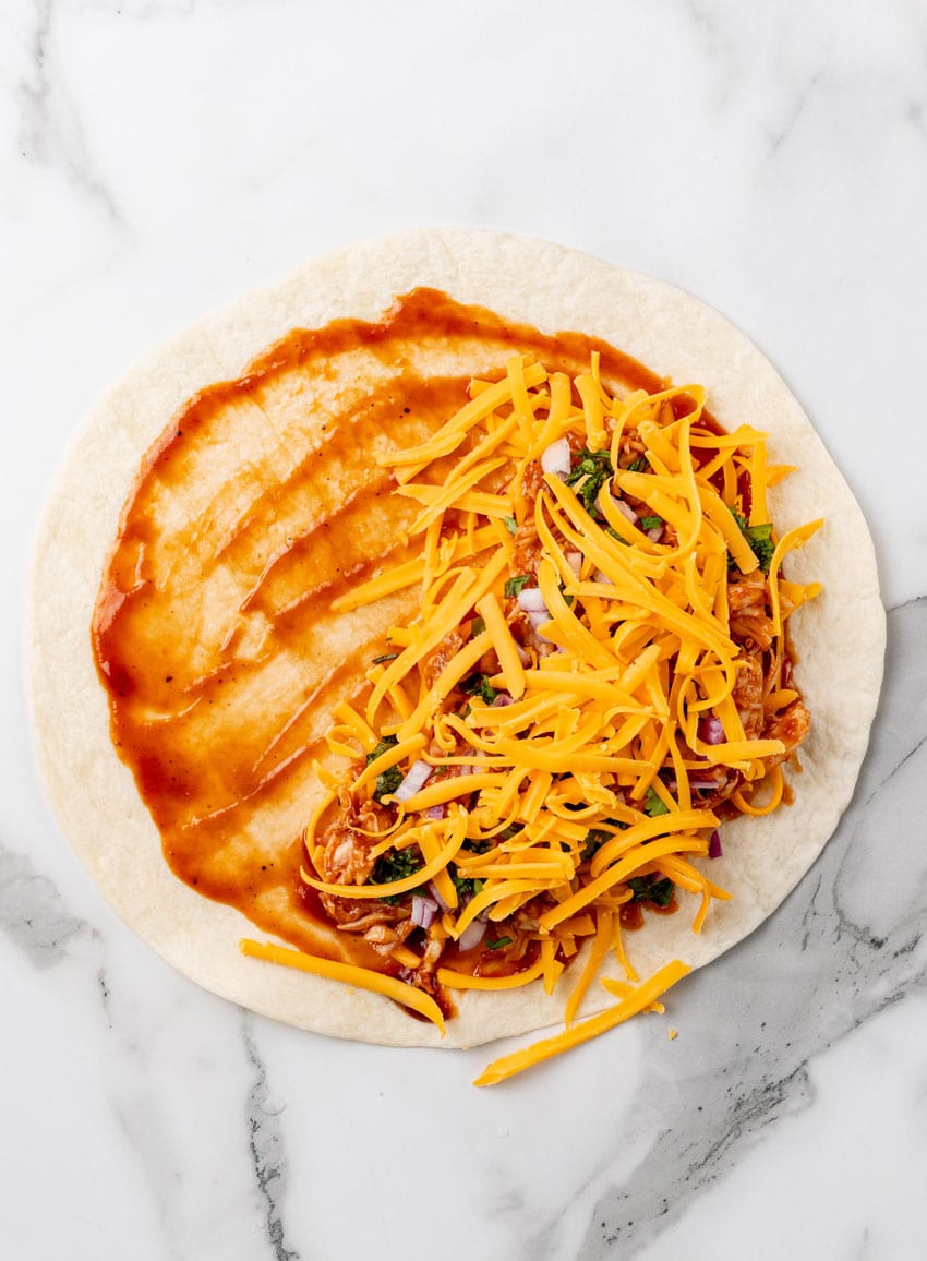 a barbecue chicken quesadillas being assembled on a marble countertop