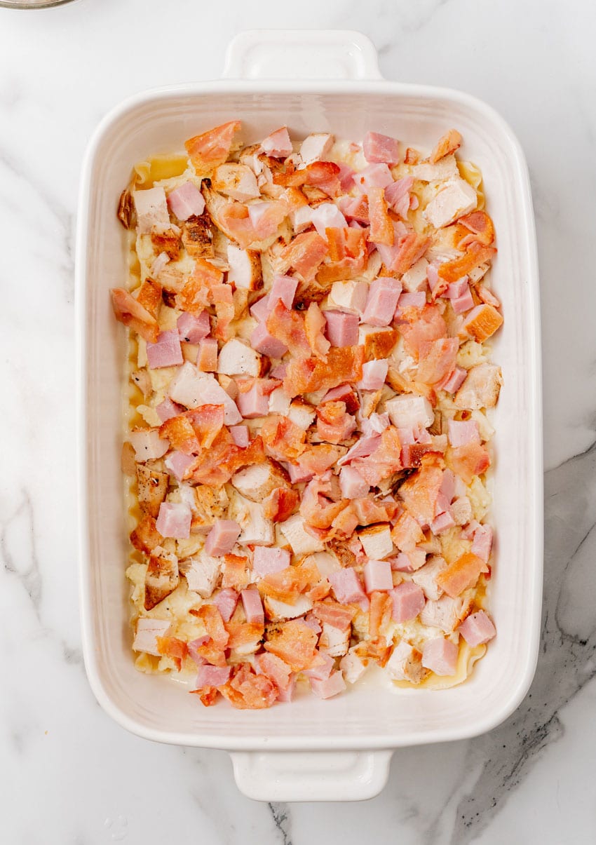 chicken cordon bleu layered in a white baking dish