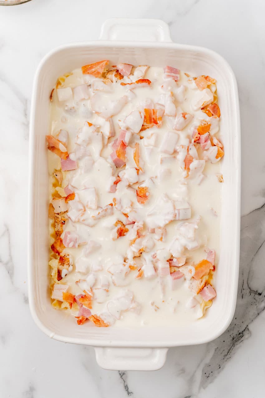 chicken cordon bleu layered in a white baking dish