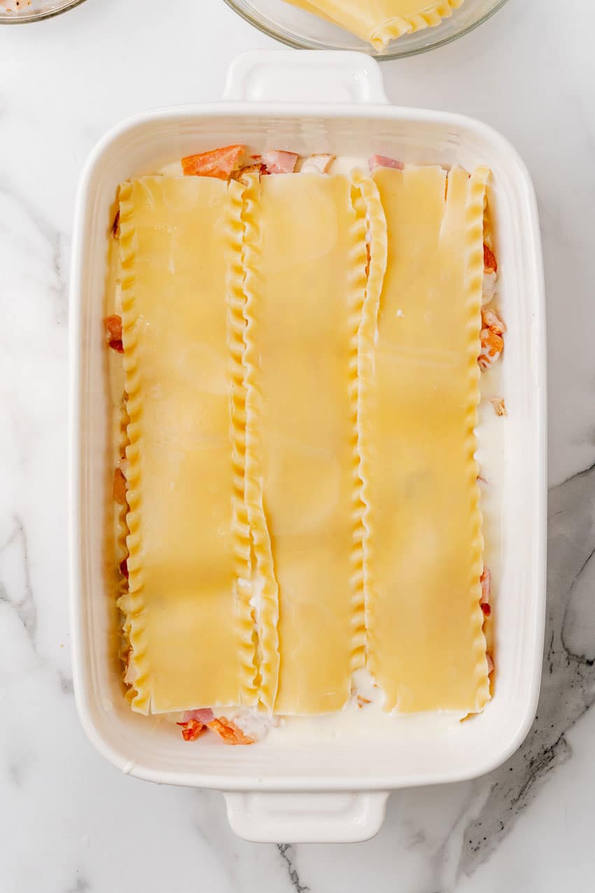 chicken cordon bleu layered in a white baking dish