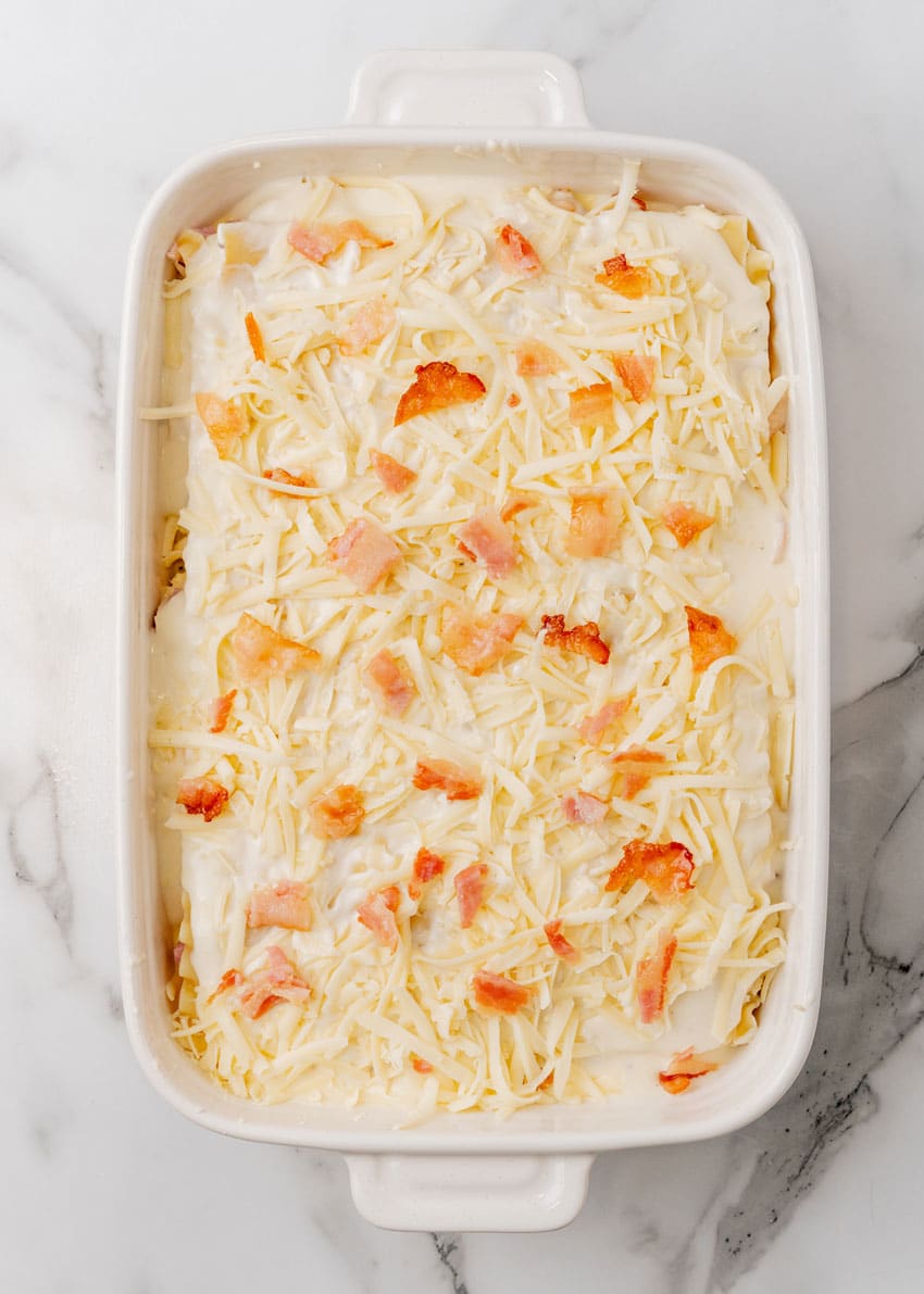 chicken cordon bleu layered in a white baking dish