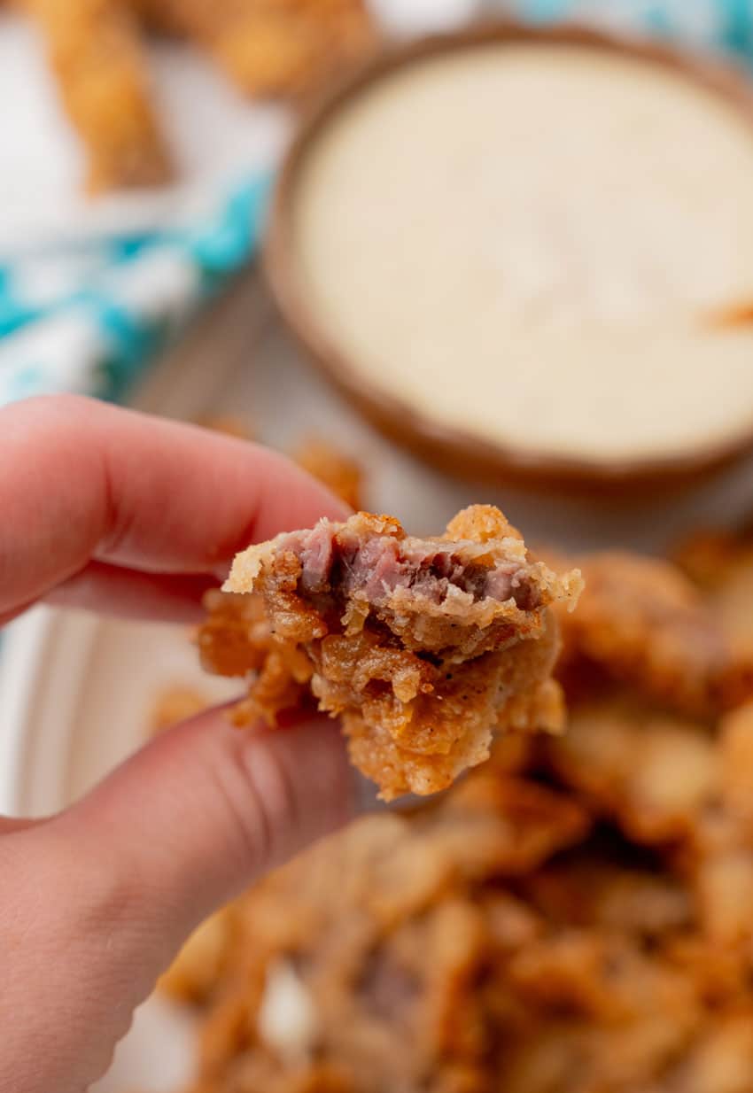 a hand holding up a homemade chicken fried steak finger