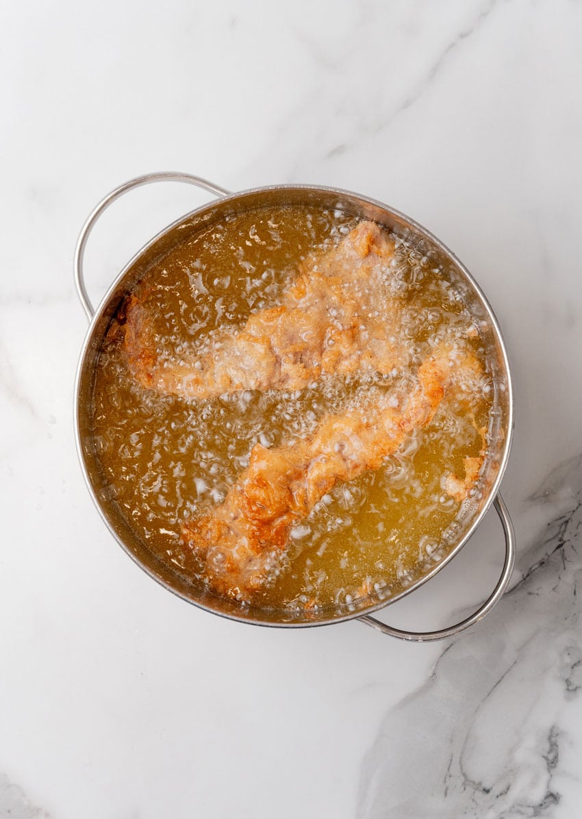 chicken fried steak fingers frying in a pot of oil