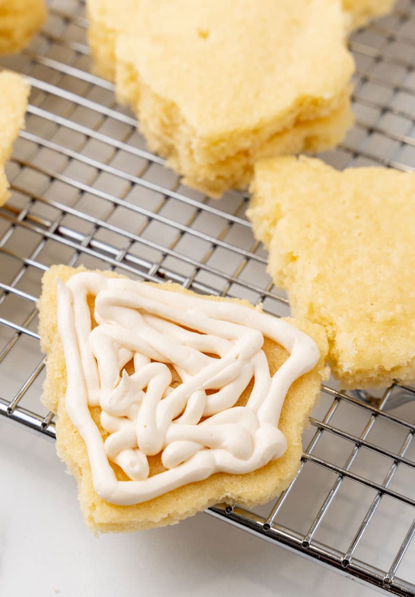 marshmallow filling piped onto a small yellow cake resting on a wire rack