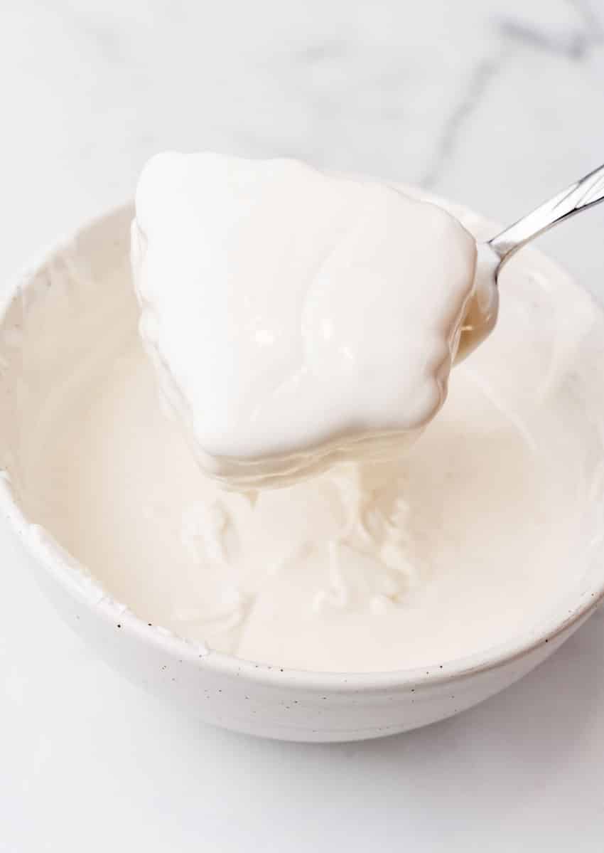 a silver fork holding up a homemade little debbie christmas tree cake covered in dripping white chocolate