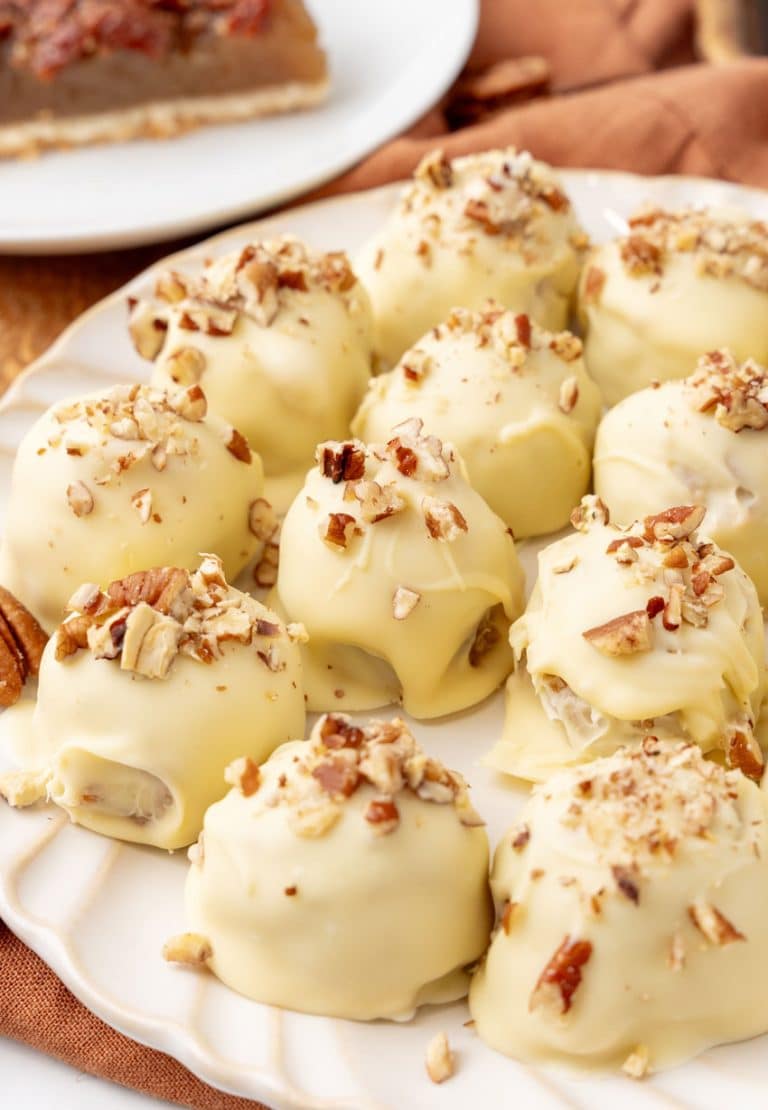 homemade pecan pie truffles covered in white chocolate on a white serving plate