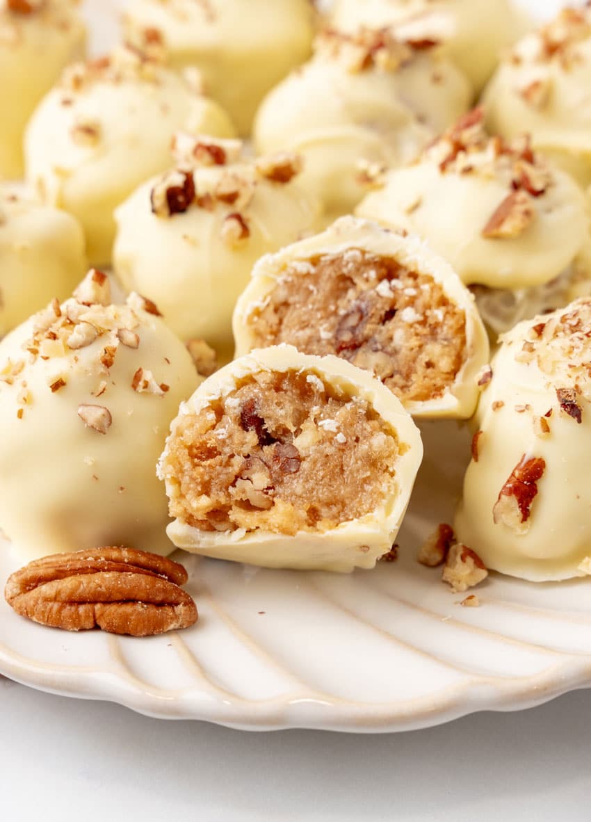 homemade pecan pie truffles covered in white chocolate on a white serving plate