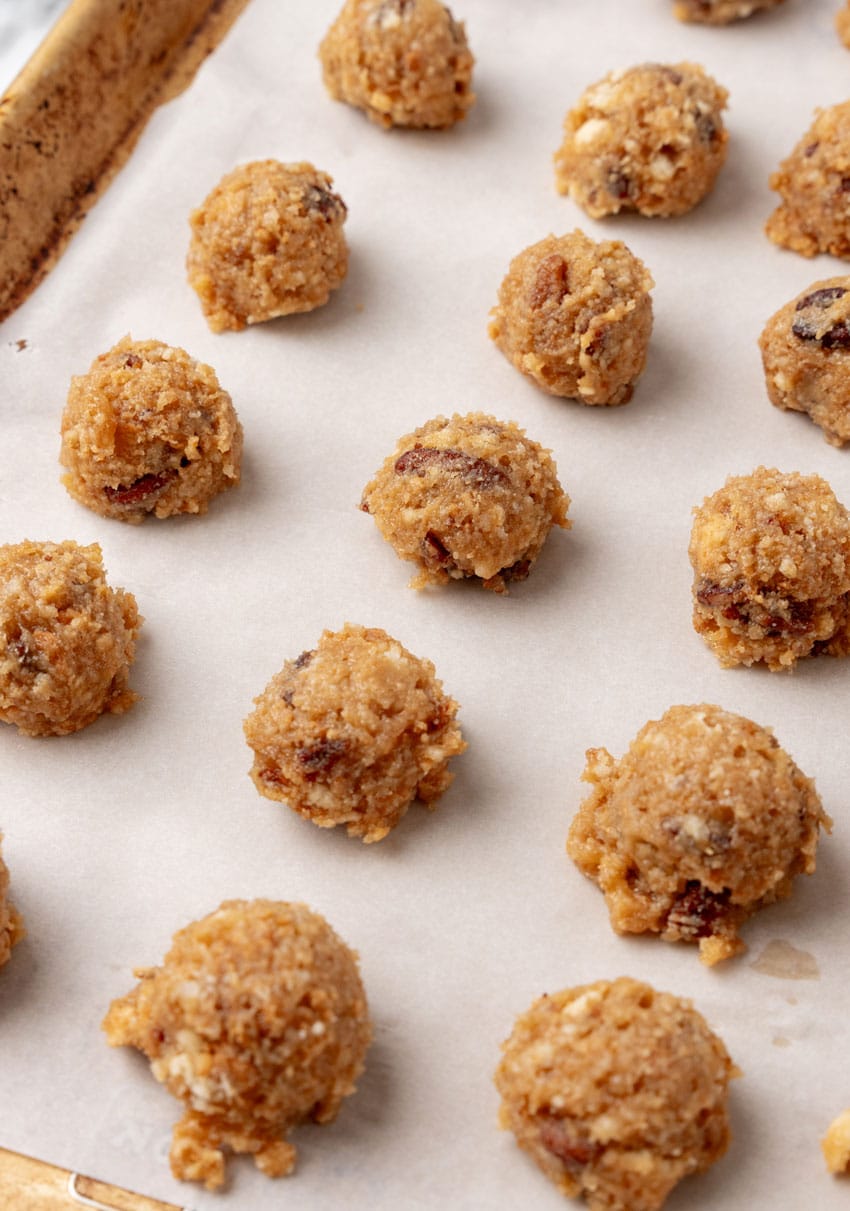 pecan pie balls arranged in rows on a parchment paper lined baking sheet