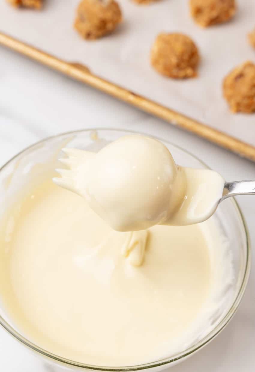 a fork holding up a white chocolate coated pecan pie ball